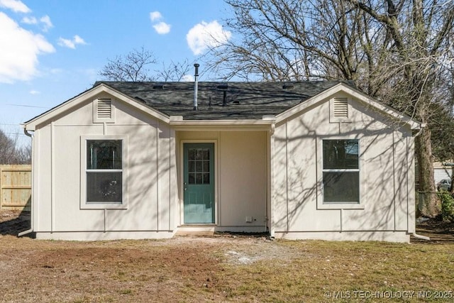 back of house with a yard, a shingled roof, and fence