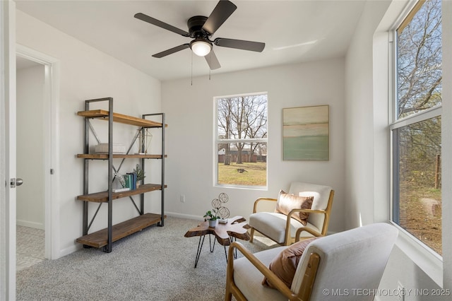 living area featuring baseboards, carpet floors, and ceiling fan