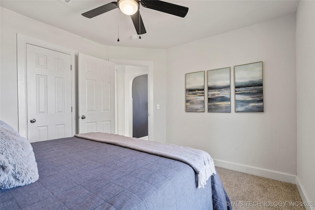 bedroom featuring carpet, baseboards, arched walkways, and a ceiling fan