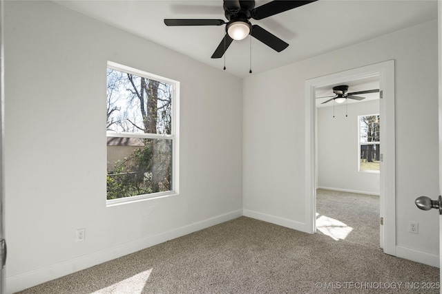 carpeted spare room featuring a ceiling fan and baseboards