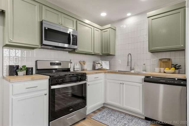 kitchen featuring a sink, tasteful backsplash, appliances with stainless steel finishes, and green cabinets