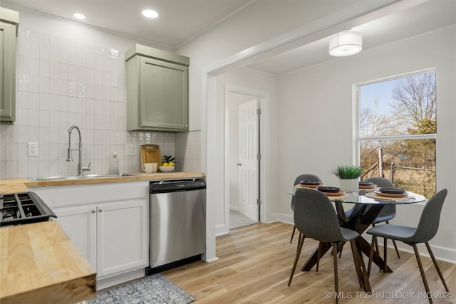 kitchen featuring tasteful backsplash, dishwasher, light wood-type flooring, wood counters, and a sink