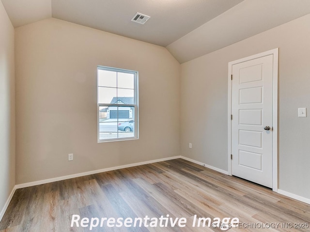 unfurnished room with lofted ceiling, wood finished floors, visible vents, and baseboards