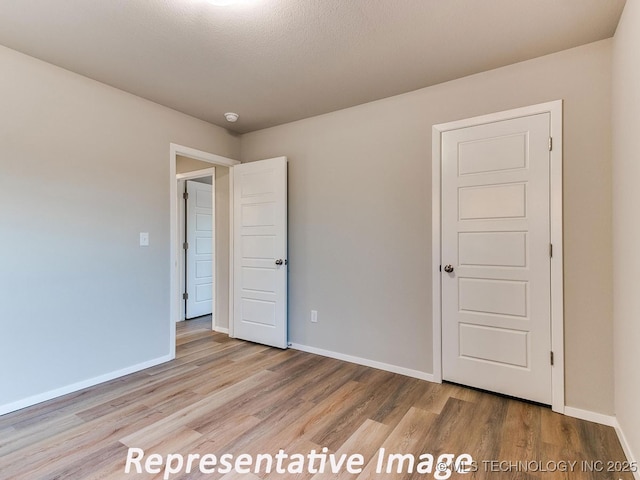 unfurnished bedroom with wood finished floors and baseboards