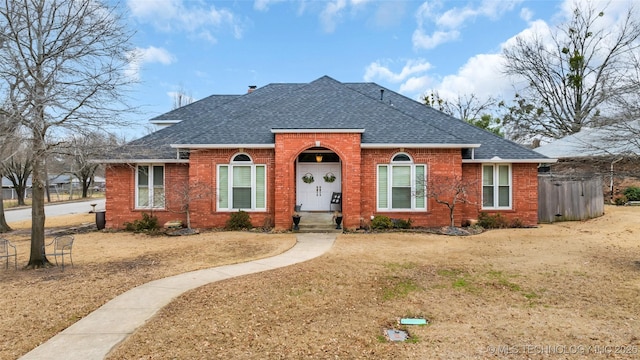 view of front of home with brick siding and roof with shingles