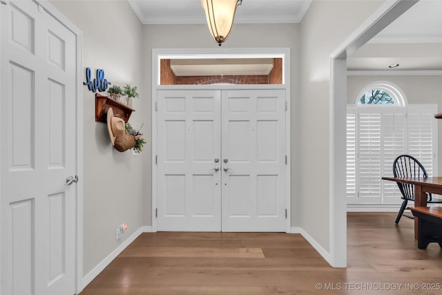 entrance foyer featuring baseboards, wood finished floors, and ornamental molding