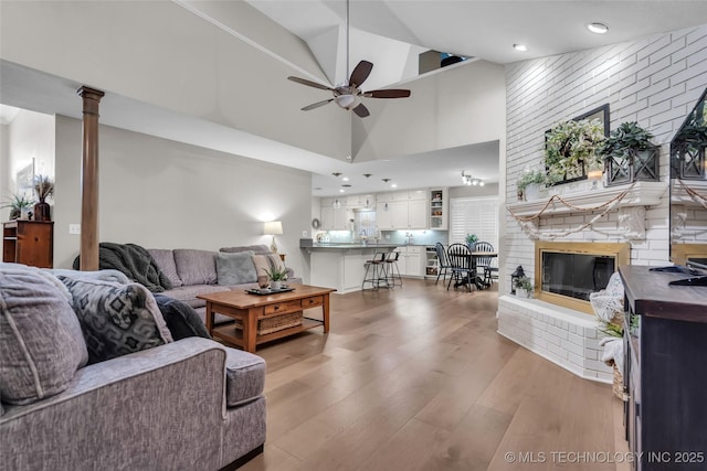 living room featuring a fireplace, a high ceiling, wood finished floors, and ceiling fan