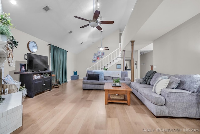 living room featuring light wood finished floors, visible vents, stairs, and a ceiling fan