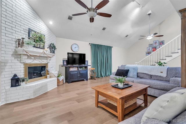 living area featuring light wood finished floors, visible vents, a fireplace, and a ceiling fan