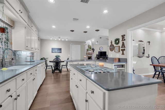 kitchen with white cabinets, tasteful backsplash, visible vents, and a sink