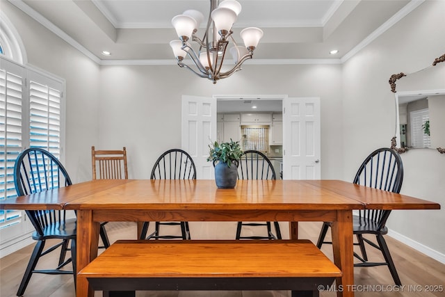 dining space featuring a tray ceiling, crown molding, a notable chandelier, and light wood-style floors