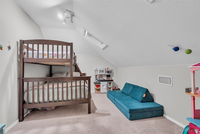 carpeted bedroom featuring lofted ceiling with skylight, visible vents, and baseboards