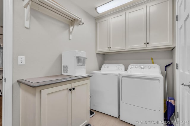 laundry area featuring washer and clothes dryer, cabinet space, and light wood-style floors