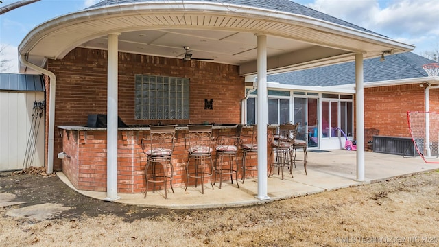 view of patio with outdoor dry bar, ceiling fan, and a sunroom