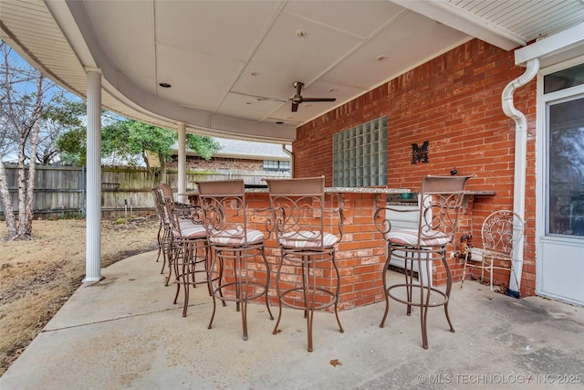 view of patio / terrace with outdoor dry bar, ceiling fan, and fence