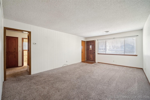 unfurnished room with carpet flooring and a textured ceiling