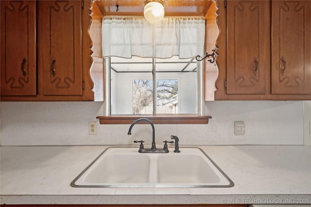 kitchen with a sink, brown cabinets, and light countertops