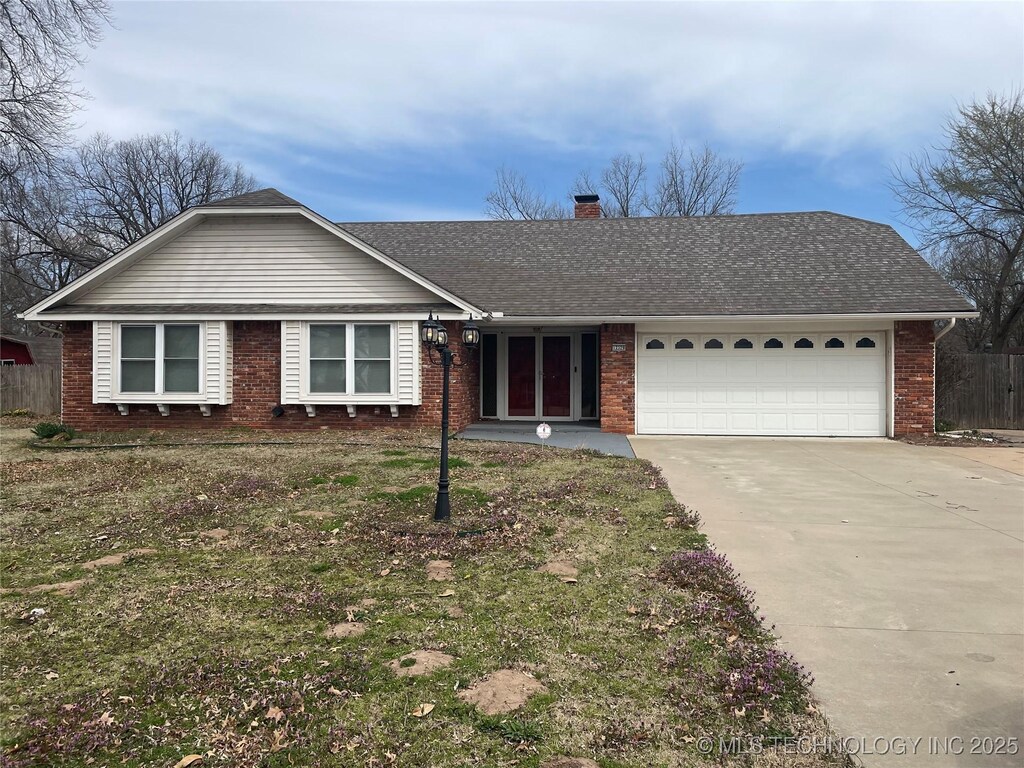 ranch-style home featuring a chimney, a shingled roof, concrete driveway, a garage, and brick siding