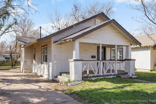 view of front facade with a porch, a front lawn, and roof with shingles