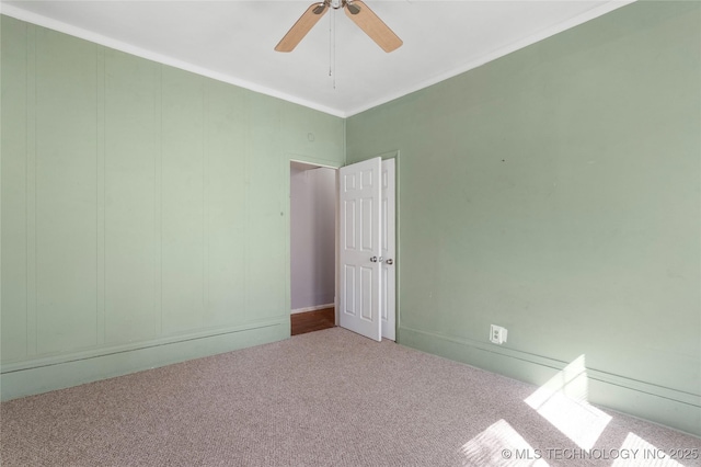 spare room featuring ceiling fan, ornamental molding, and carpet flooring