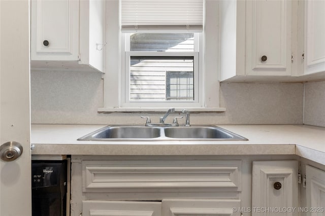 kitchen with white cabinetry, light countertops, dishwasher, and a sink