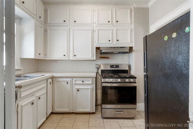 kitchen with freestanding refrigerator, light countertops, under cabinet range hood, white cabinetry, and gas range