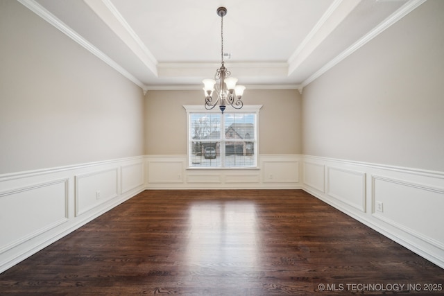 unfurnished dining area featuring a raised ceiling, a notable chandelier, dark wood finished floors, and crown molding