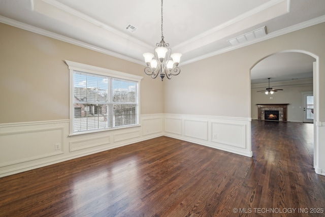 spare room with arched walkways, visible vents, a lit fireplace, and a tray ceiling