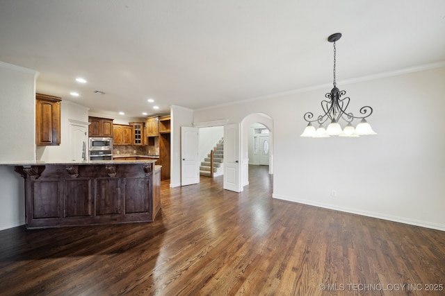 kitchen with arched walkways, appliances with stainless steel finishes, a peninsula, an inviting chandelier, and baseboards