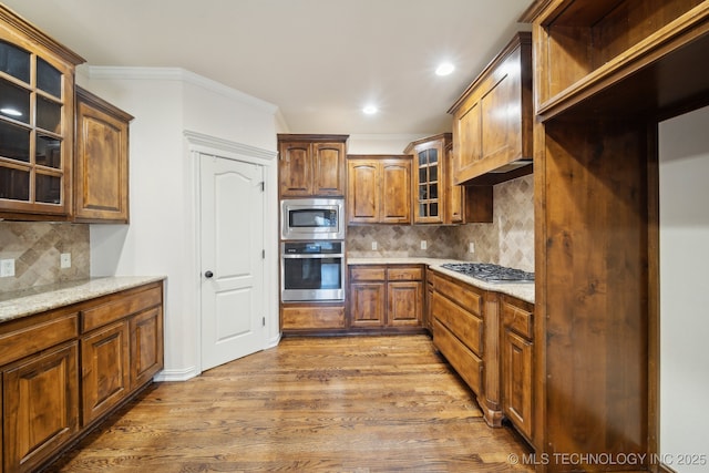 kitchen with crown molding, glass insert cabinets, wood finished floors, and appliances with stainless steel finishes