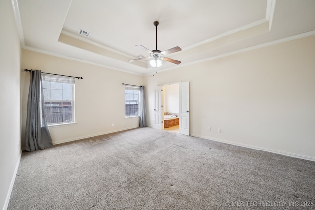 unfurnished bedroom with visible vents, a raised ceiling, ornamental molding, carpet floors, and baseboards