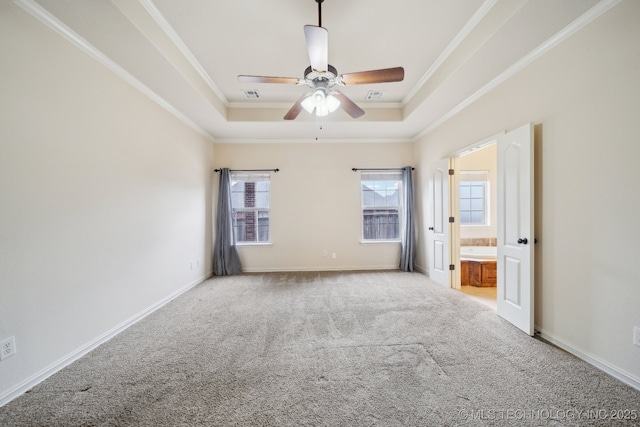 carpeted empty room featuring a ceiling fan, visible vents, baseboards, a tray ceiling, and crown molding