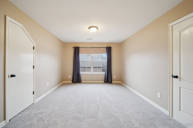 empty room with light colored carpet, visible vents, and baseboards