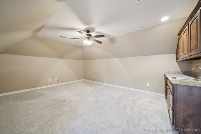 additional living space featuring lofted ceiling, a sink, baseboards, light colored carpet, and ceiling fan