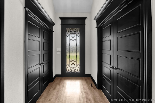 foyer with baseboards and light wood-style floors