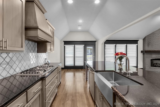 kitchen featuring light wood-style flooring, stainless steel appliances, decorative backsplash, lofted ceiling, and custom exhaust hood