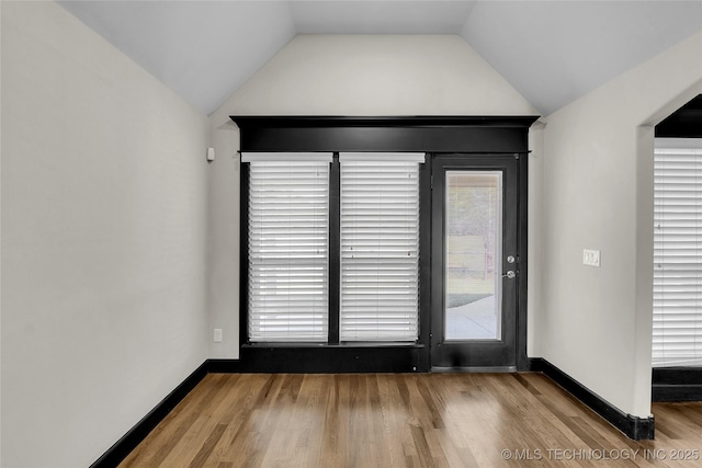 interior space featuring baseboards, lofted ceiling, and wood finished floors