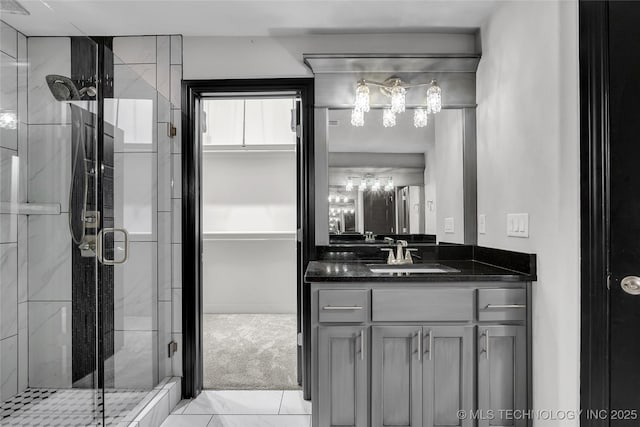 bathroom with a notable chandelier, a stall shower, and vanity