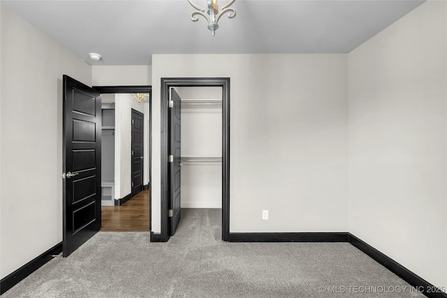 unfurnished bedroom with a closet, baseboards, a spacious closet, and carpet flooring