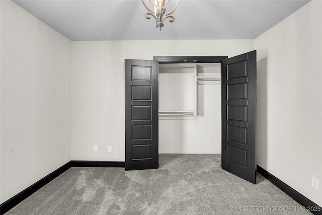 unfurnished bedroom with a notable chandelier, carpet flooring, and baseboards