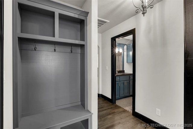 mudroom featuring dark wood-type flooring, baseboards, visible vents, and a sink