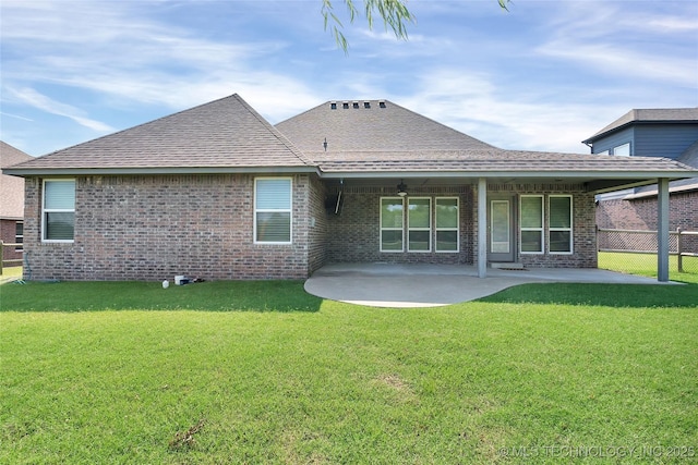 back of property featuring a patio area, brick siding, roof with shingles, and a lawn