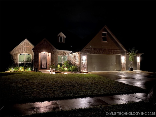 view of front of home with brick siding, driveway, and a yard