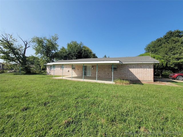 rear view of property featuring a patio, a lawn, and brick siding