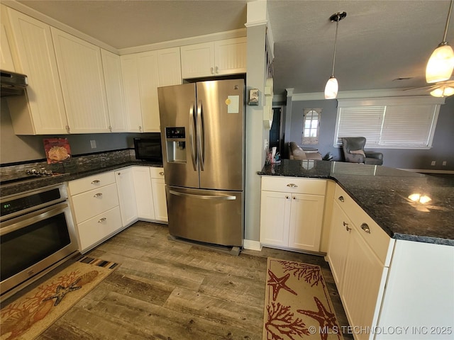 kitchen with dark wood-type flooring, appliances with stainless steel finishes, a peninsula, and white cabinets