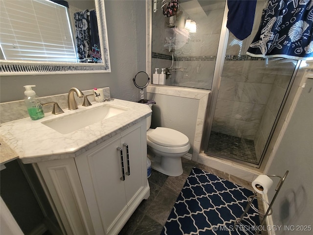 bathroom with a shower stall, vanity, toilet, and a textured wall