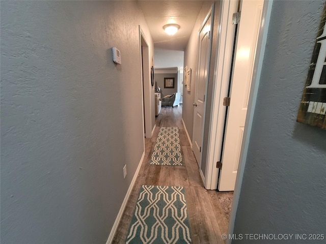 corridor with wood finished floors and a textured wall