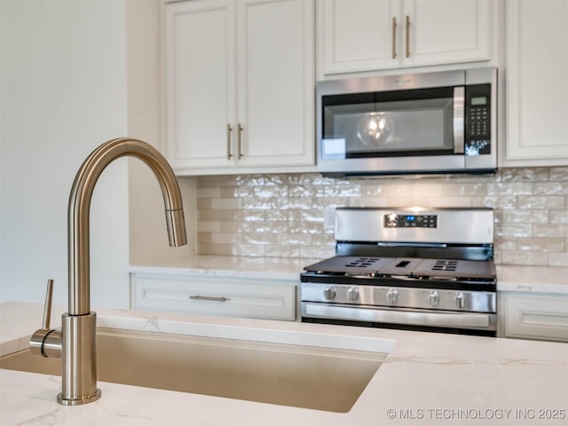 13404 E 123rd Pl, Collinsville, OK 74021 - kitchen with white cabinets, a sink, tasteful backsplash, light stone countertops, and appliances with stainless steel finishes
