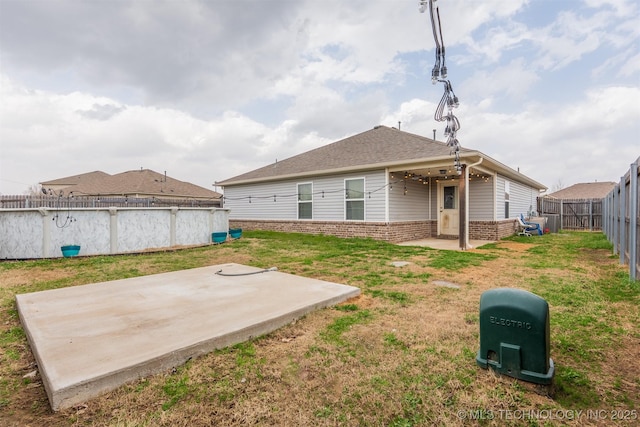 back of house with brick siding, a swimming pool, a lawn, a fenced backyard, and a patio area