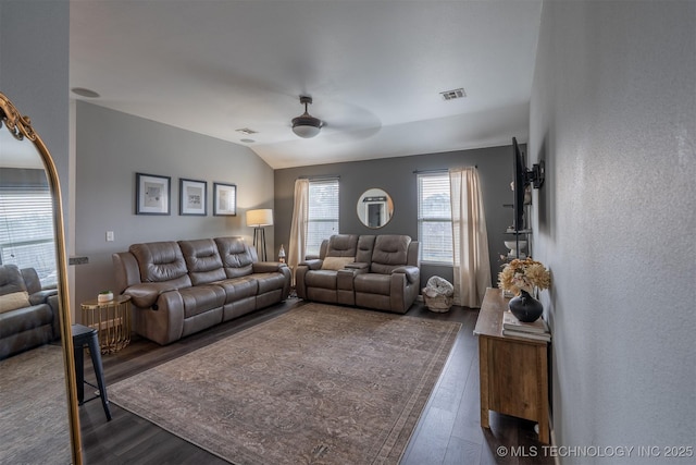 living room featuring dark wood finished floors, vaulted ceiling, a ceiling fan, and visible vents